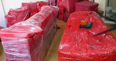 Kırmızı koruma ambalajına sarılmış koltuk takımı ve sehpalar