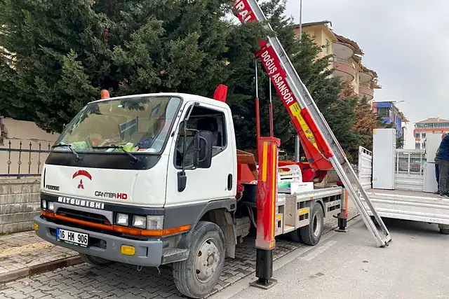 Sokakta kurulmuş Doğuş asansörlü aracı ve kırmızı asansör kolu