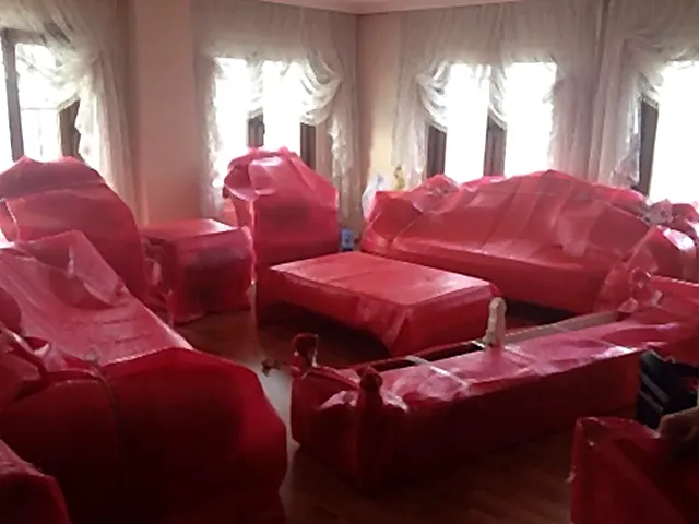 Pembe koruma örtüsüne sarılmış salon takımı ve sehpalar