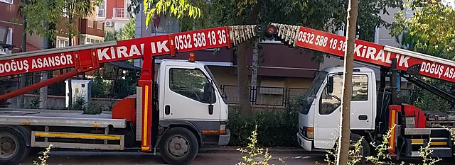 Sokakta yan yana duran, kırmızı asansör kolunda Doğuş Asansör yazan iki araç